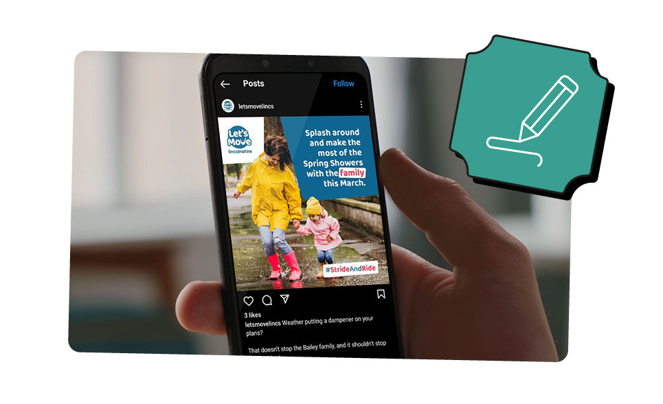 A close-up photo of a person holding their smartphone which displays a branded design for a social media post.