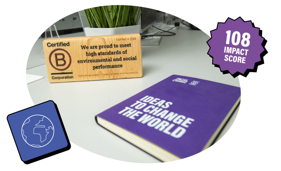 A wooden plaque awarded for qualifying as a B Corp next to a Social Change branded notebook, the plaque says: 
Certified B Corporation. We are proud to meet high standards of environmental and social performance.