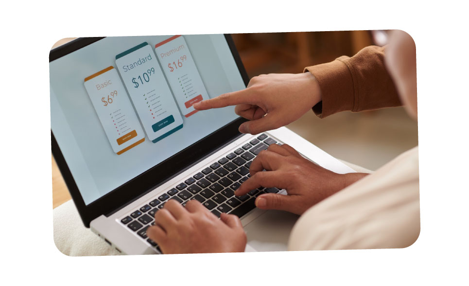 A close up of a laptop screen showing subscription options for a service. A person points at the screen whilst another sits with the laptop on their lap.