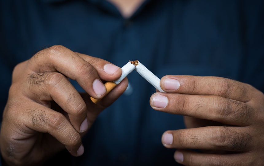 A close-up of a man's hands breaking a cigarette in half.