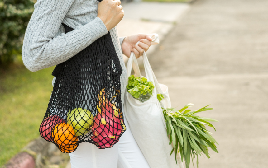 Woman using a reusable net bag with fruit and veg in