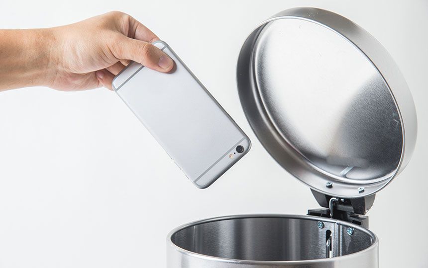 Someone is throwing their smartphone in an open-top bin.