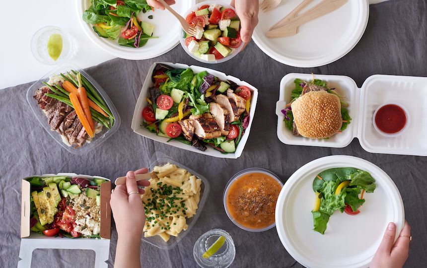 Hands reach for a range of colourful, healthy food dishes, including salads and pasta.