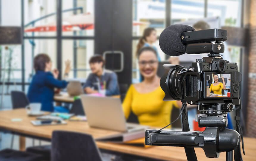 A young woman films herself working and researching in a study hall.