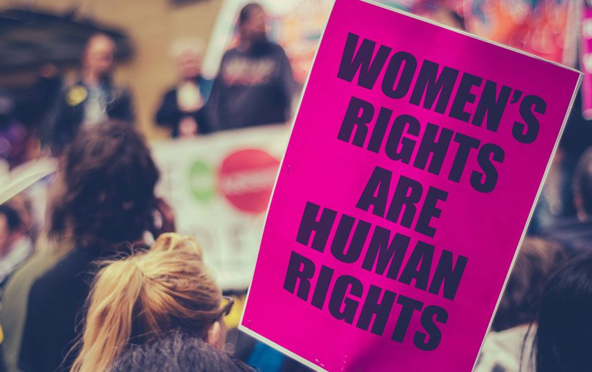 A large pink poster which says 'Women's rights are human rights' is shown at a march.