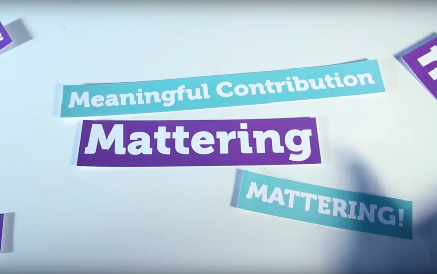 Atop a table are purple and teal signs which say 'Mattering' and 'Meaningful contribution'.