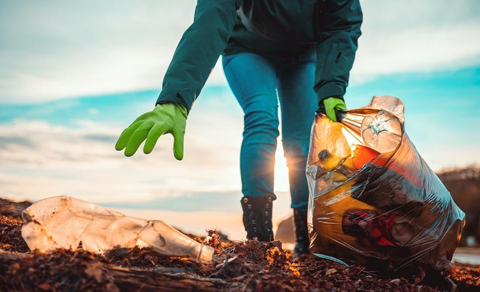 A person picking up litter on a beach.