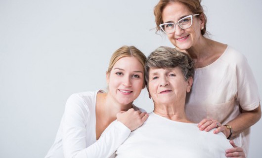 Three generations of women are smiling together; a mother, daughter and grandmother.