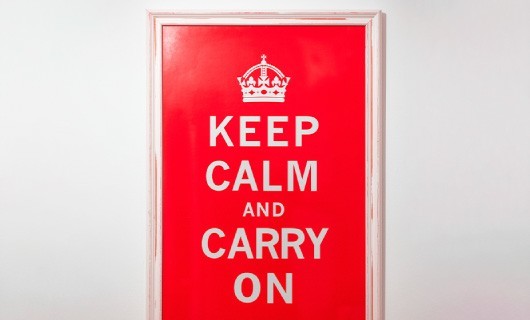 A keep calm and carry on poster in a white frame.
