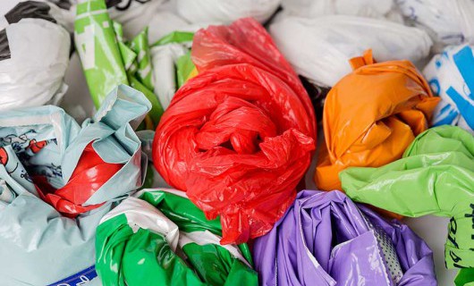 Several folded carrier bags in a range of colours.