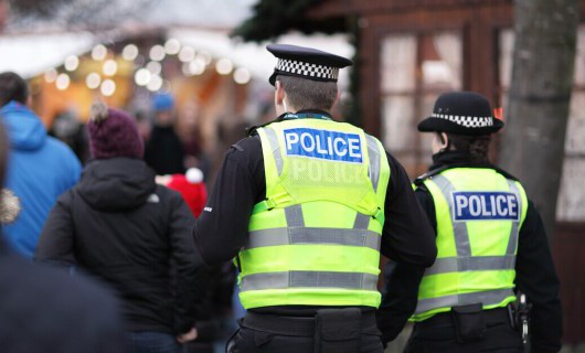 Two police officers walking through a busy winter market event.