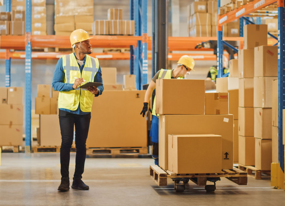 An employer in a factory setting, assessing standards and making notes.