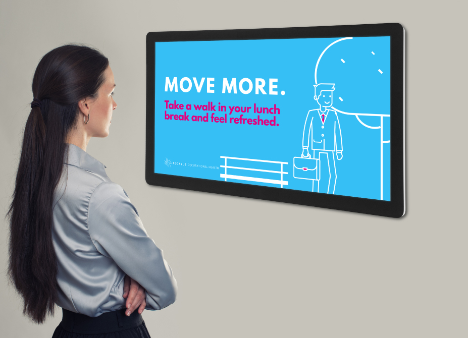 A woman views a digital display recommending employees go on walks during lunch breaks.