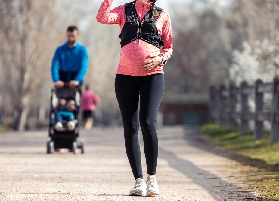 A pregnant lady walking in the park.