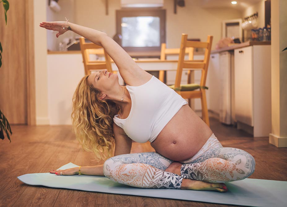 A pregnant woman doing yoga in her living room.