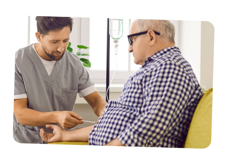 A male caregiver placing an intravenous line (IV) into their elderly male care-users arm.