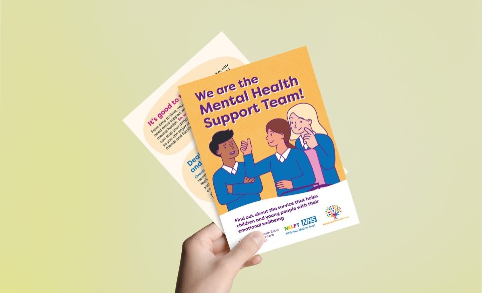 A hand holding the cover and an inside page of a flyer made for secondary schools students. The design shows an illustration of 3 students talking to each other.