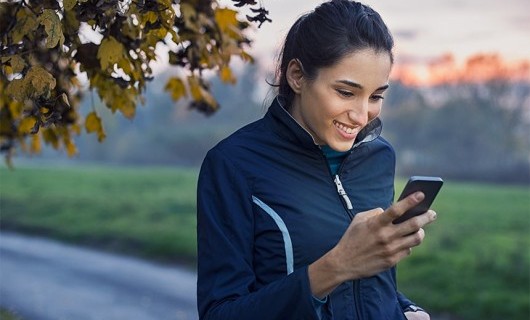 A woman checks her phone during a run.