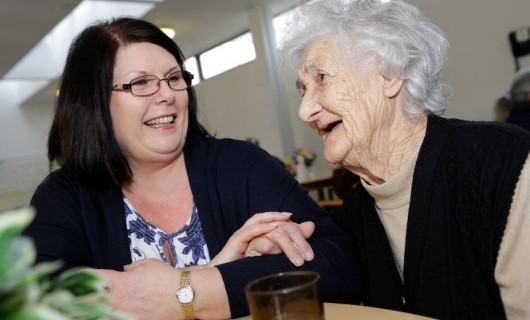 A care giver and her care user laughing and smiling together.