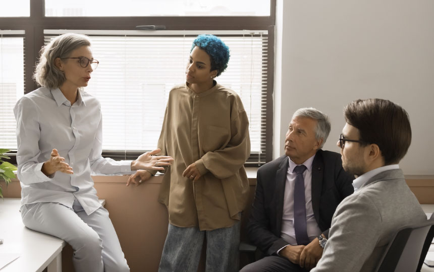 A group of diverse colleagues engaged in discussion in the office.