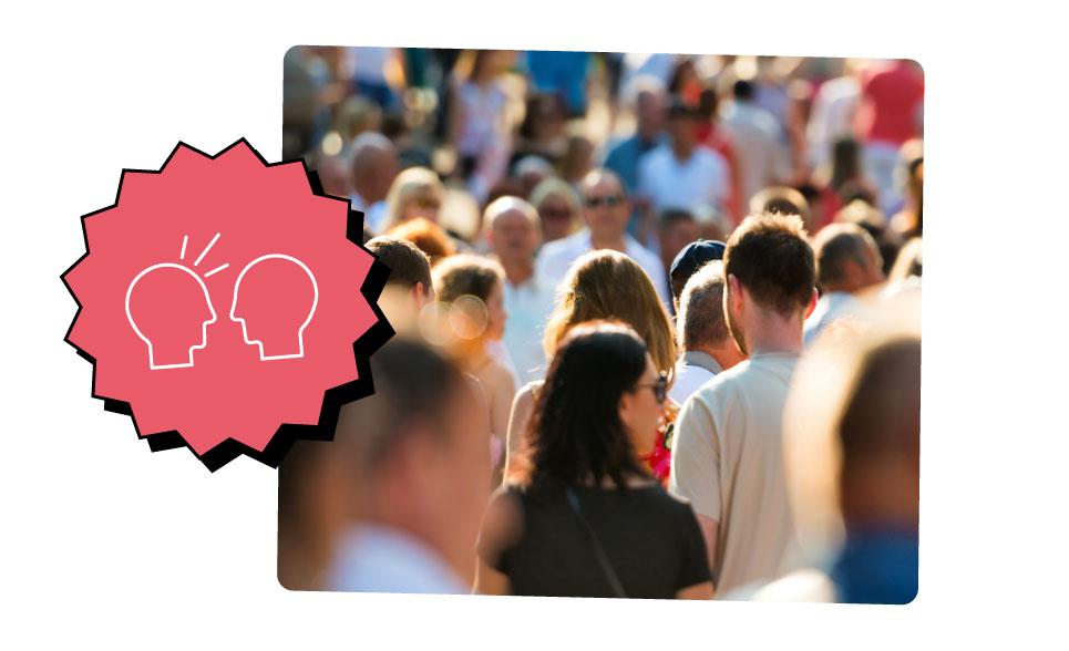 A crowd of people walk down a very busy street in daylight.