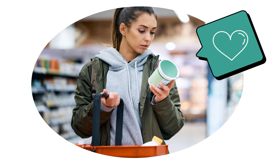 A woman in the supermarket dairy aisle reading the label on a tub of yoghurt.